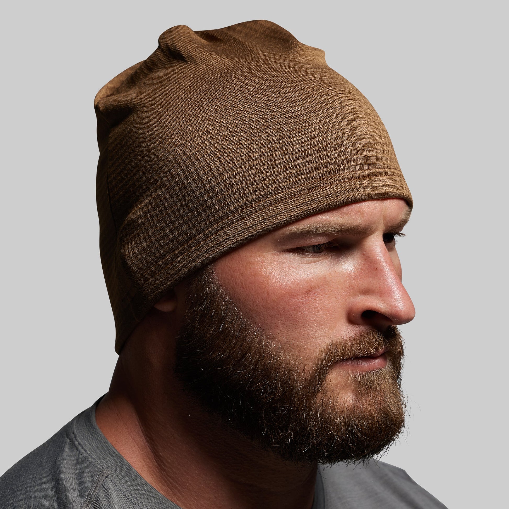 Man wearing a brown beanie against a gray background