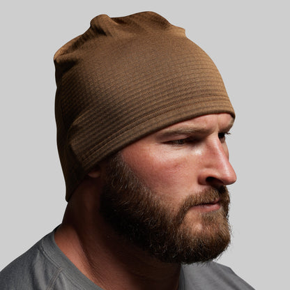 Man wearing a brown beanie against a gray background