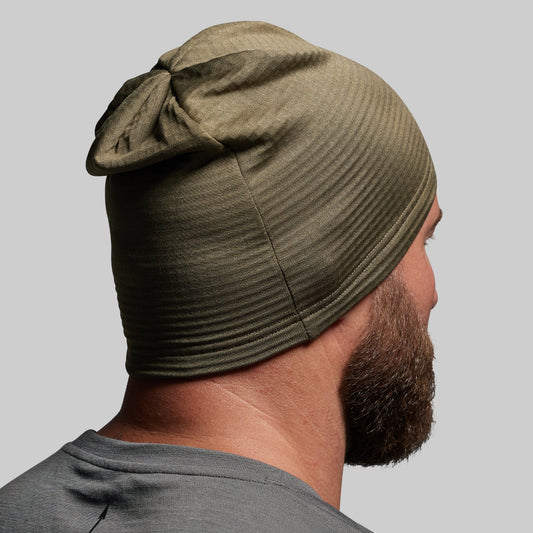Person wearing a green beanie on a gray background