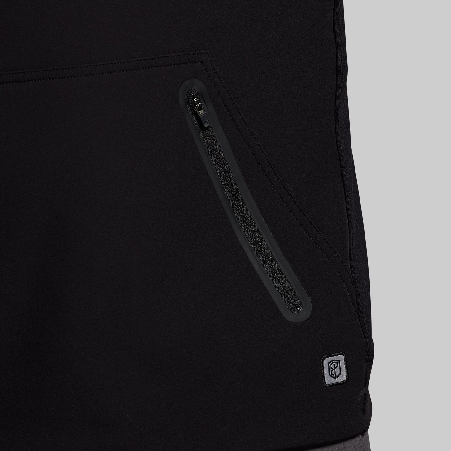 Close-up of a black jacket with a zipper and a brand logo on a light gray background
