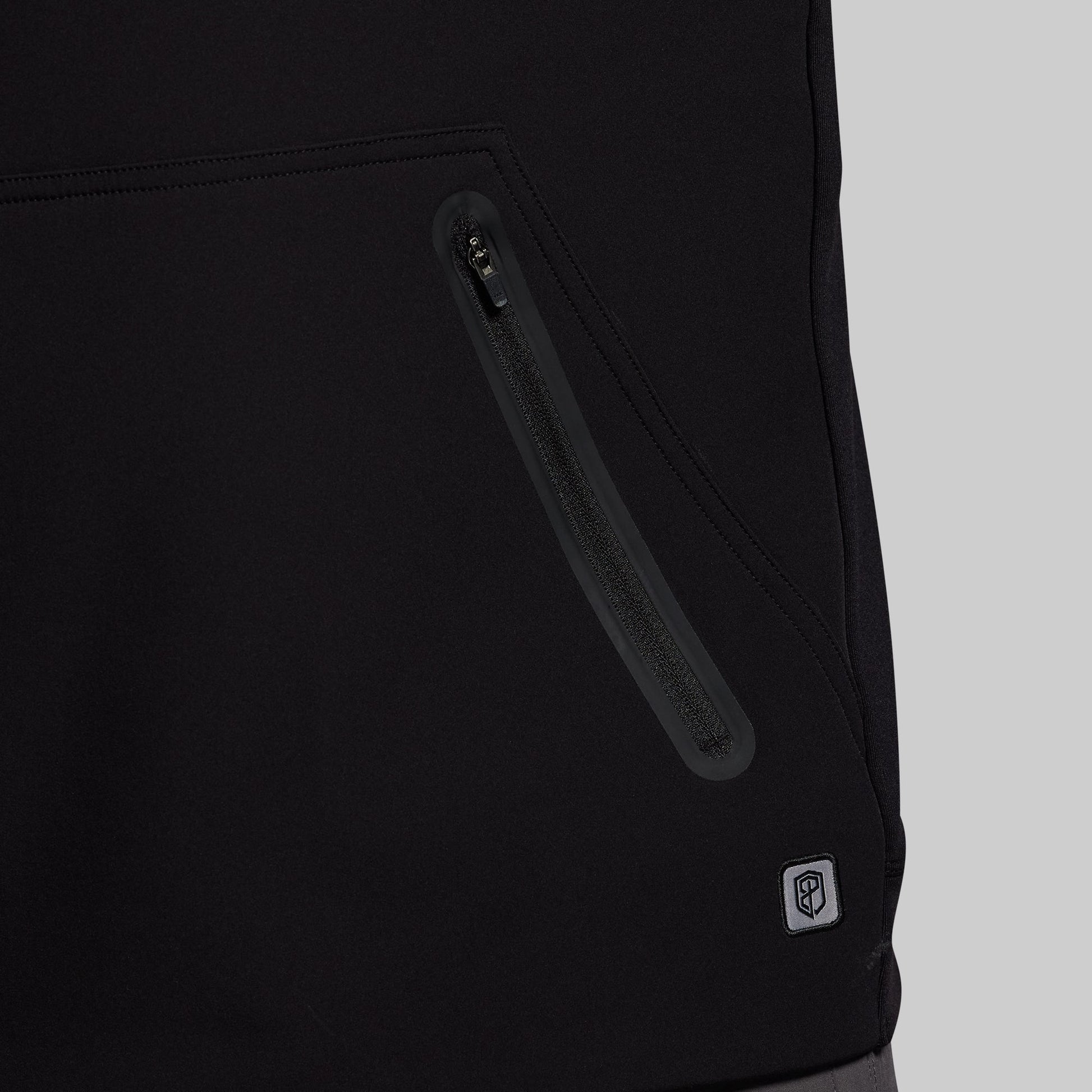 Close-up of a black jacket with a zipper and a brand logo on a light gray background