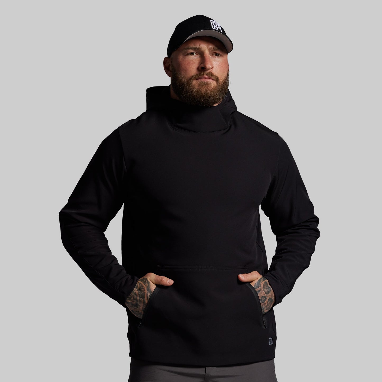 Man wearing a black hoodie and cap on a gray background