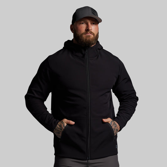 Man wearing a black hoodie and cap on a gray background