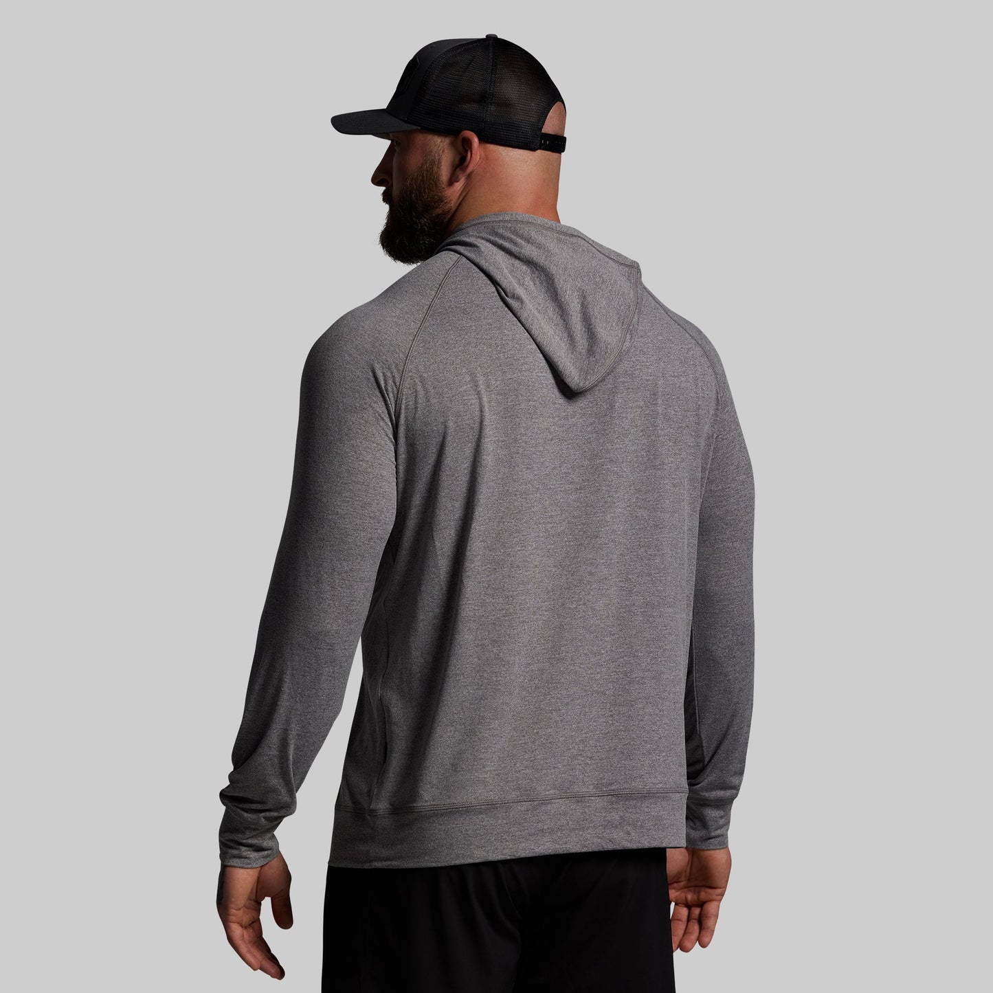 Man wearing a gray hoodie and black cap on a light gray background