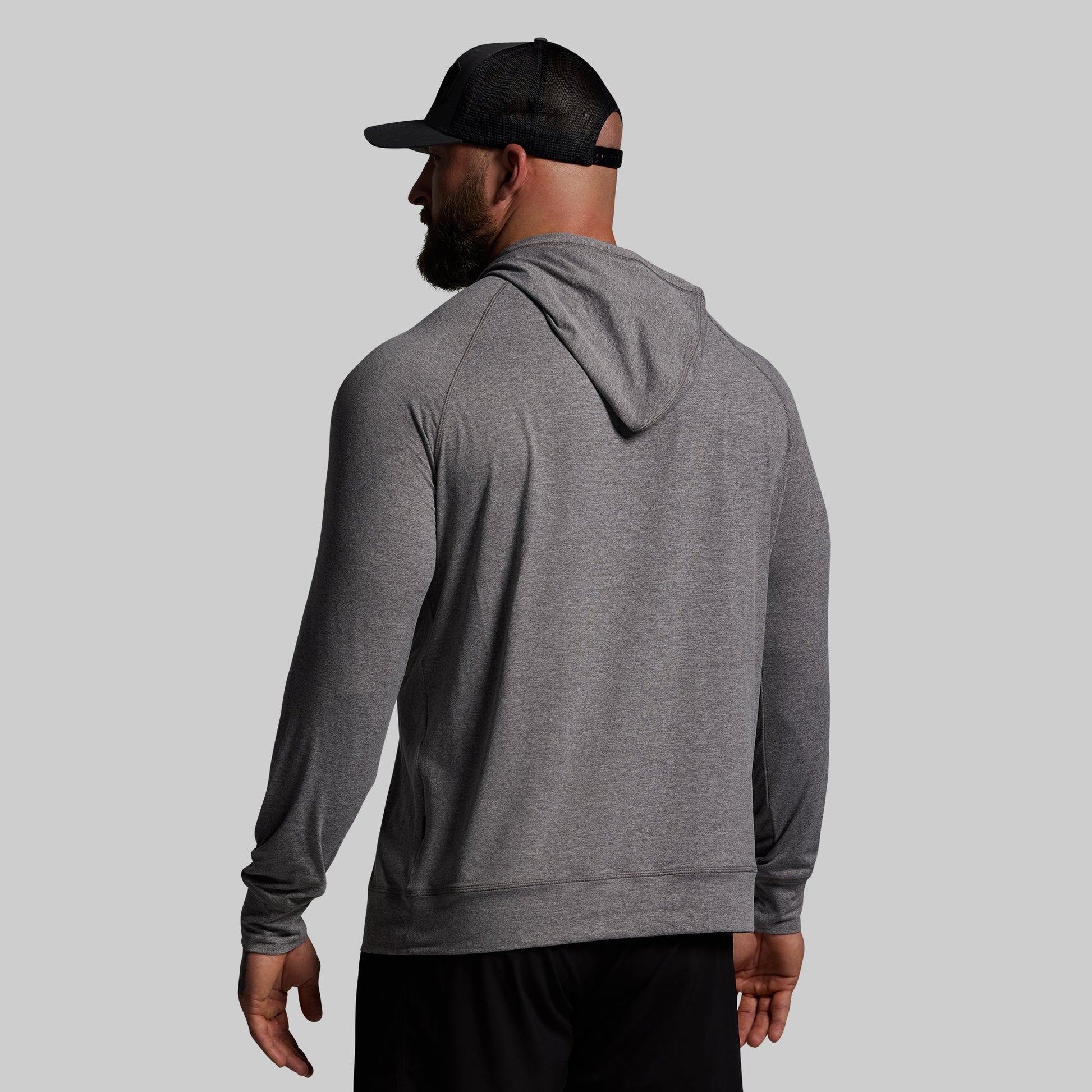 Man wearing a gray hoodie and black cap on a light gray background
