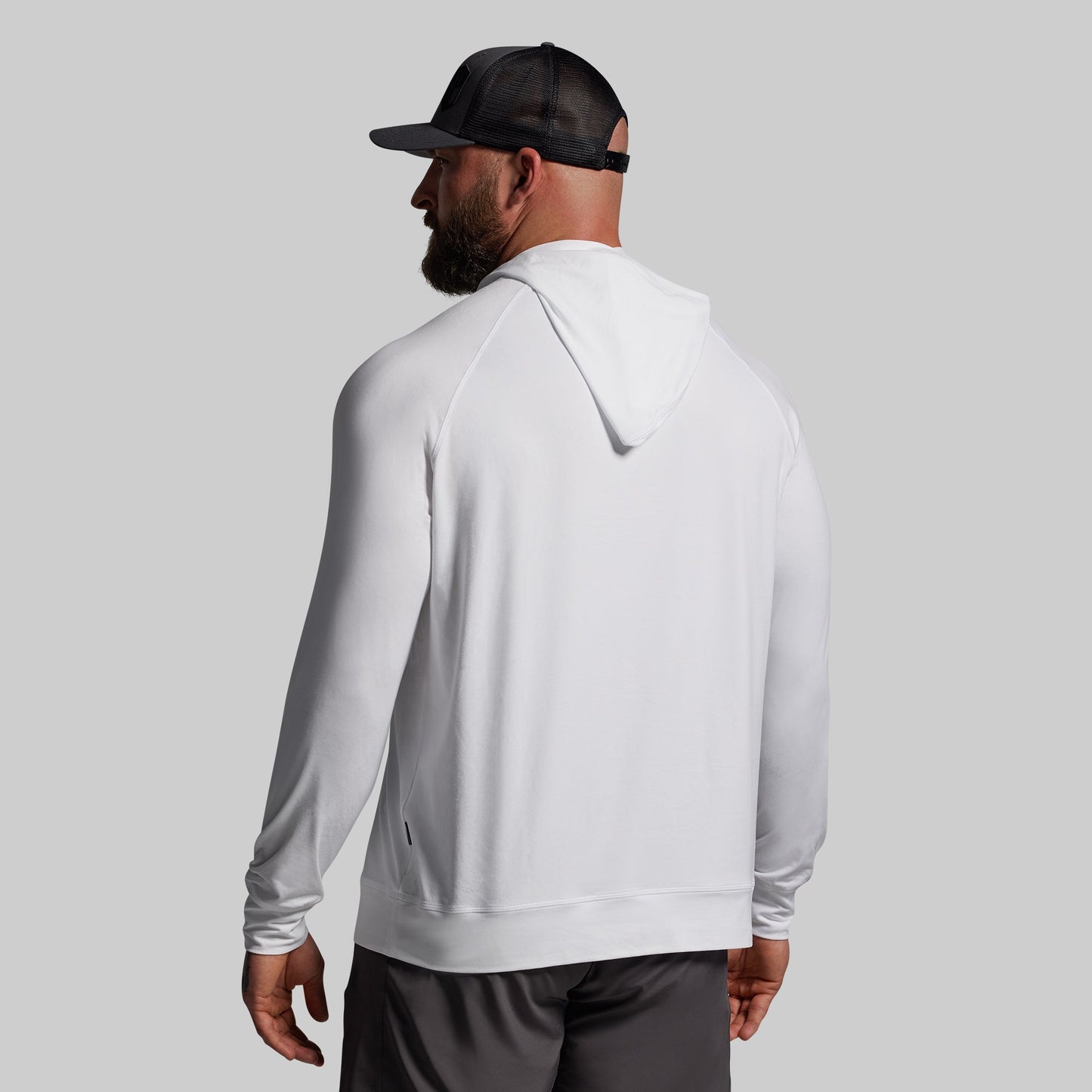 Person wearing a white hoodie and black cap on a gray background