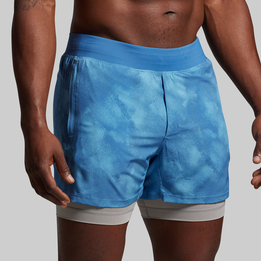 Blue athletic shorts worn by a person on a gray background