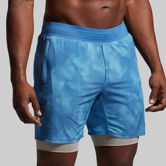 Blue athletic shorts worn by a person on a gray background