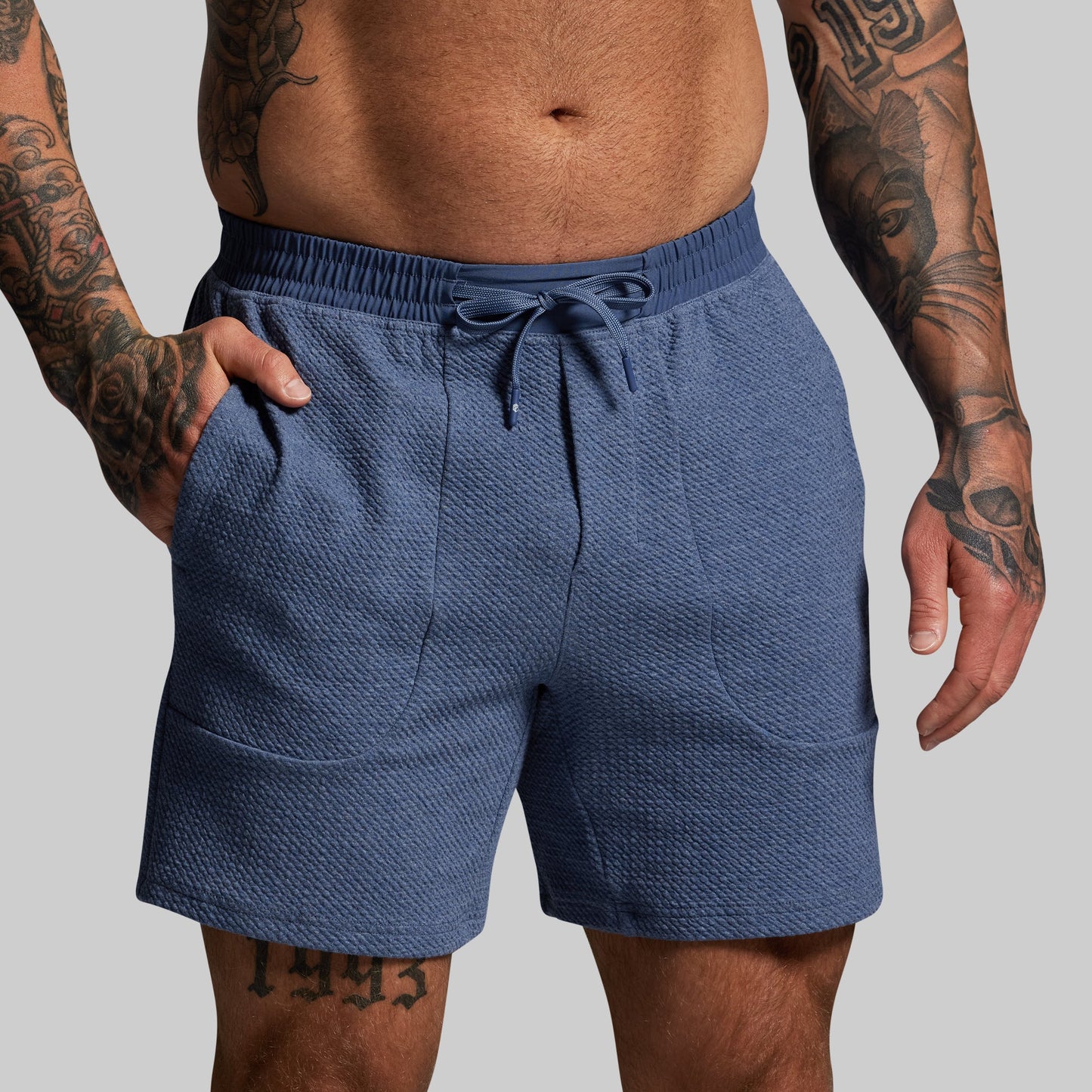 Man wearing blue shorts on a gray background