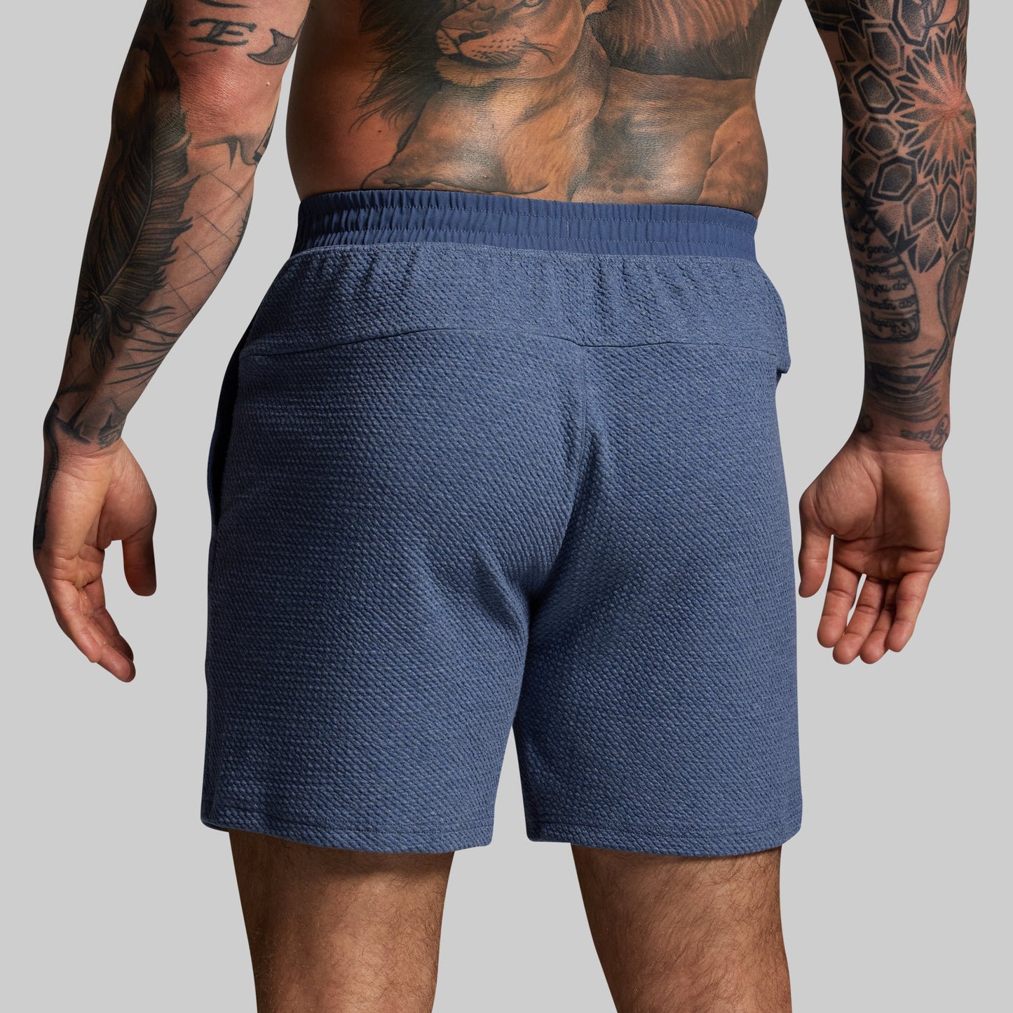 Person wearing blue shorts with a plain background