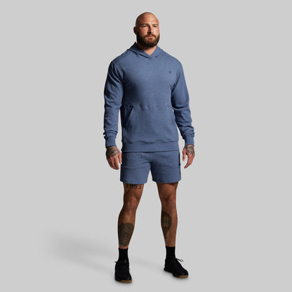 Man wearing a blue hoodie and shorts set on a gray background