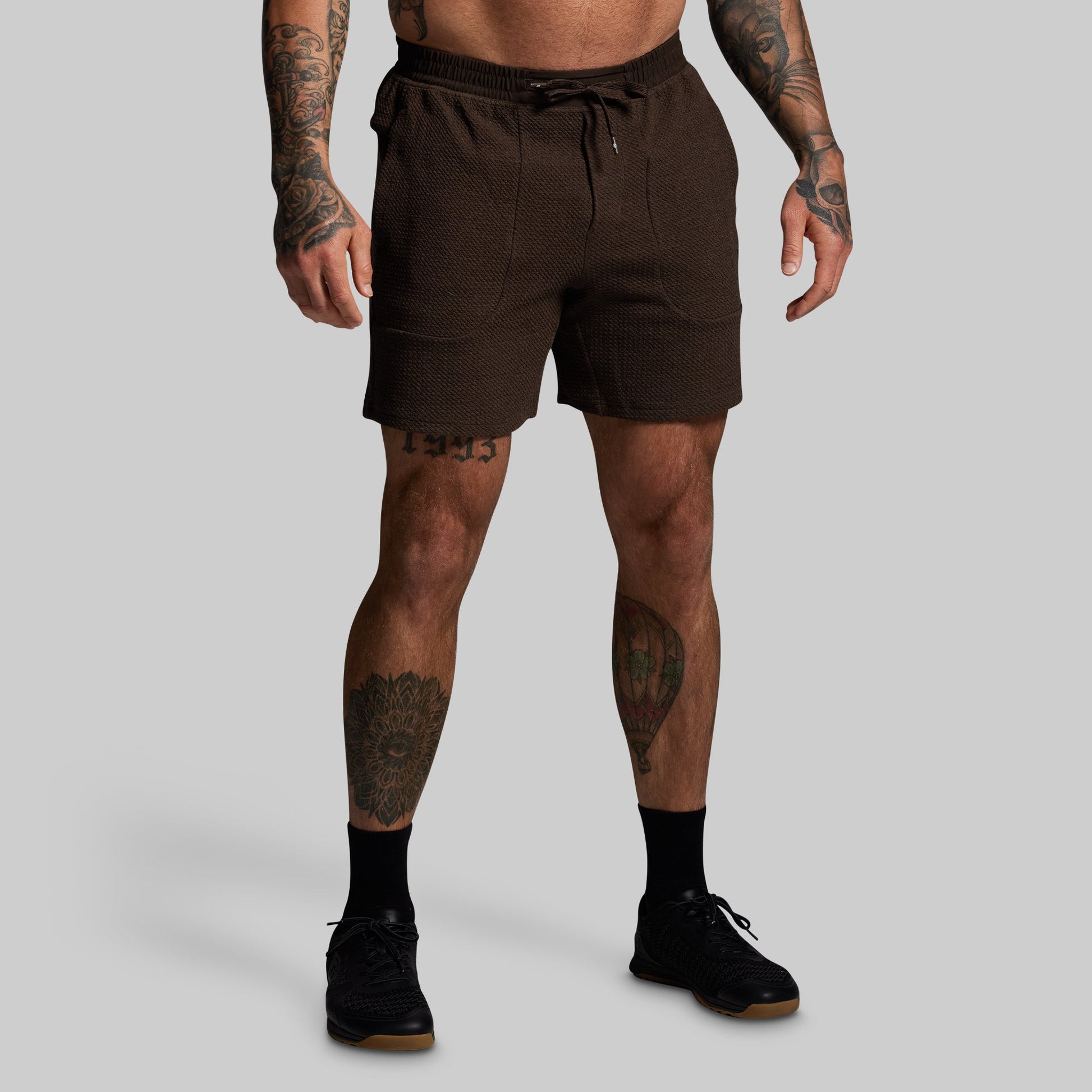 Man wearing brown shorts on a gray background