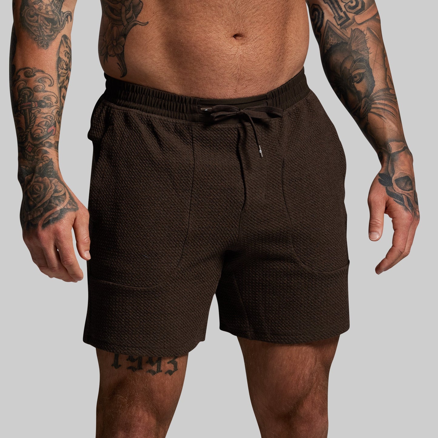 Person wearing brown shorts on a plain background