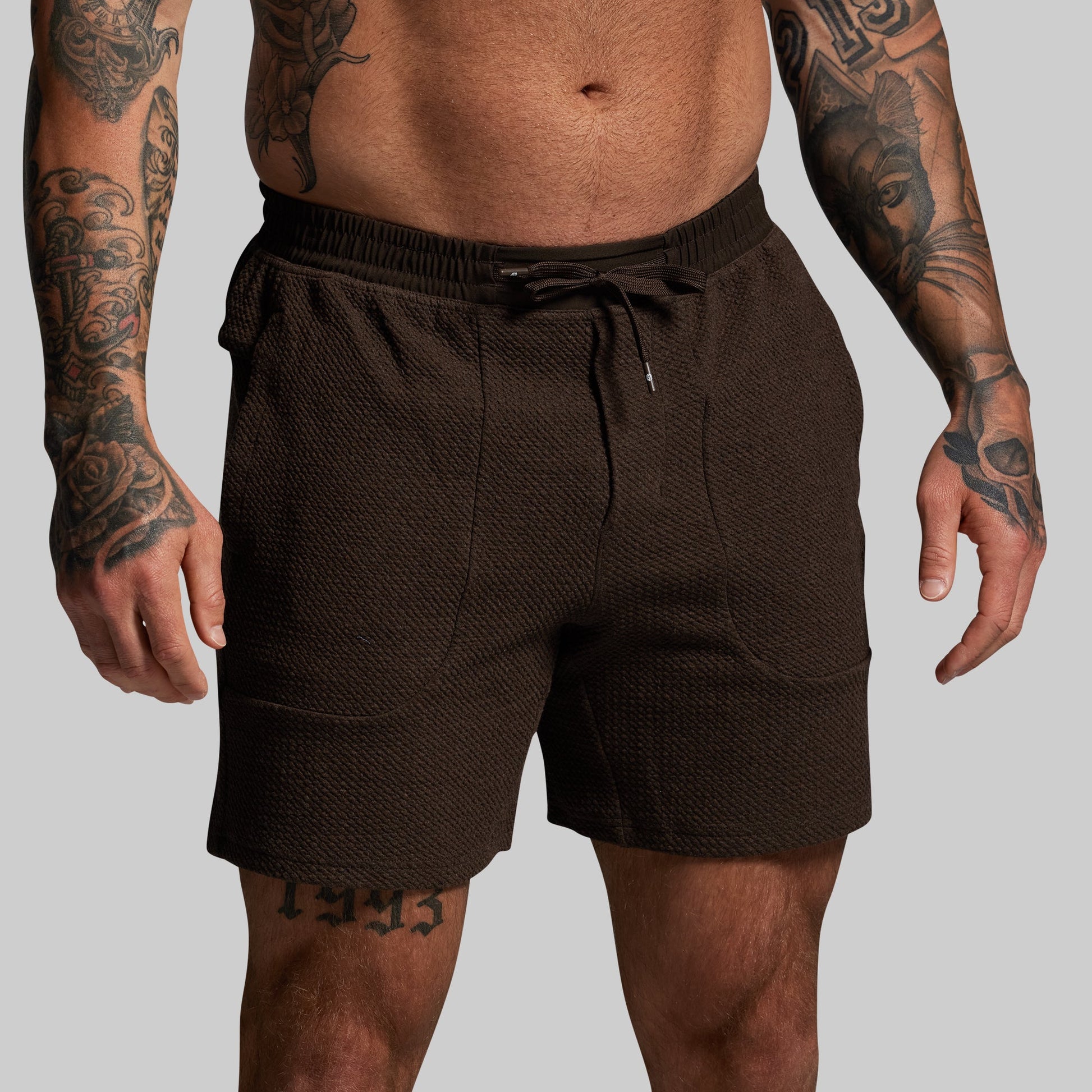 Person wearing brown shorts on a plain background