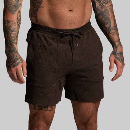 Person wearing brown shorts on a plain background