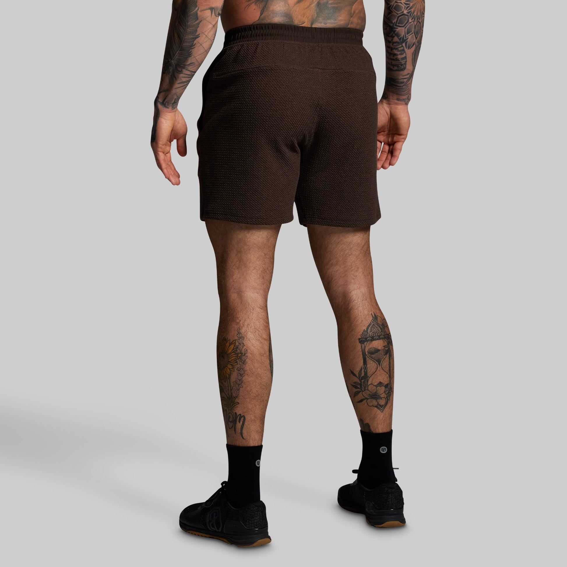 Person wearing brown shorts on a gray background