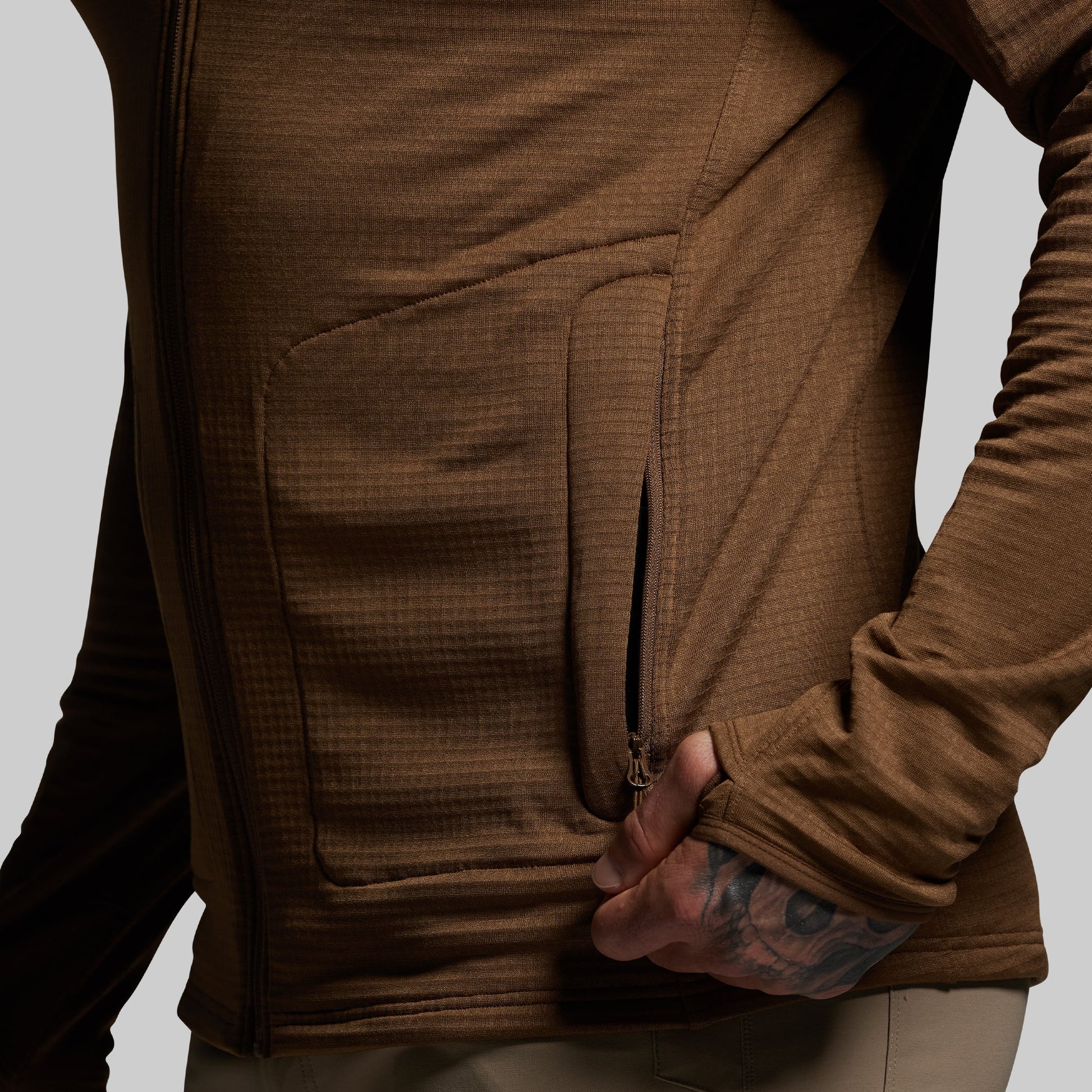 Brown hoodie with a focus on the pocket area against a neutral background