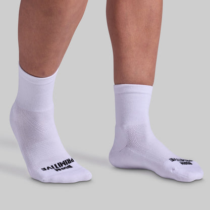 A pair of white, half crew socks with cushioned panels, displayed on a pair of legs. The socks have black text branding on the side.