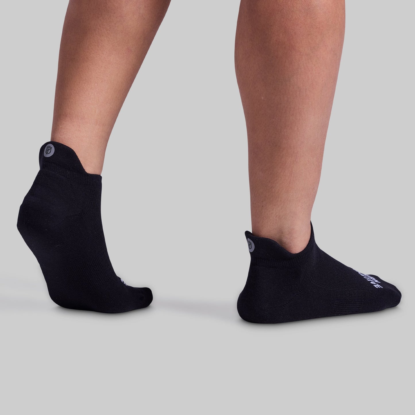 A pair of black performance ankle socks designed for comfort and breathability, featuring cushioned panels and a tab at the back to prevent rubbing.