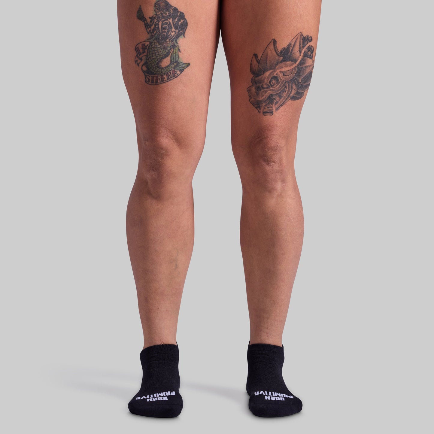 Person wearing black socks with visible brand name on a plain background