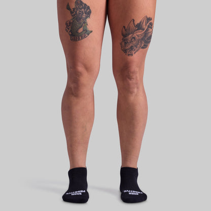 Person wearing black socks with visible brand name on a plain background