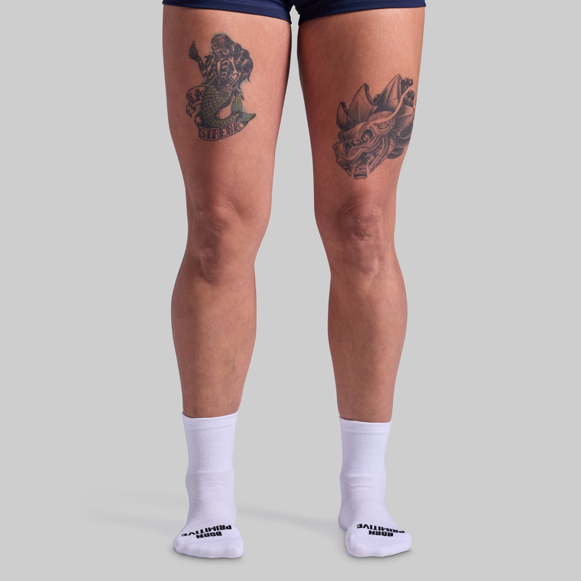 Person wearing white socks with a brand logo on a light gray background