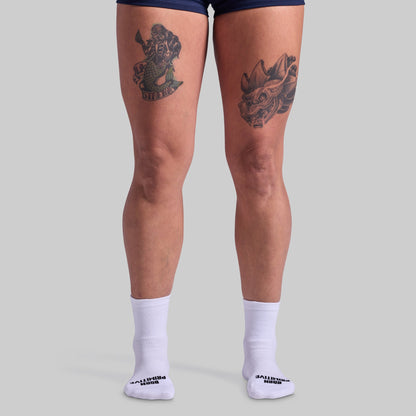 Person wearing white socks with a brand logo on a light gray background