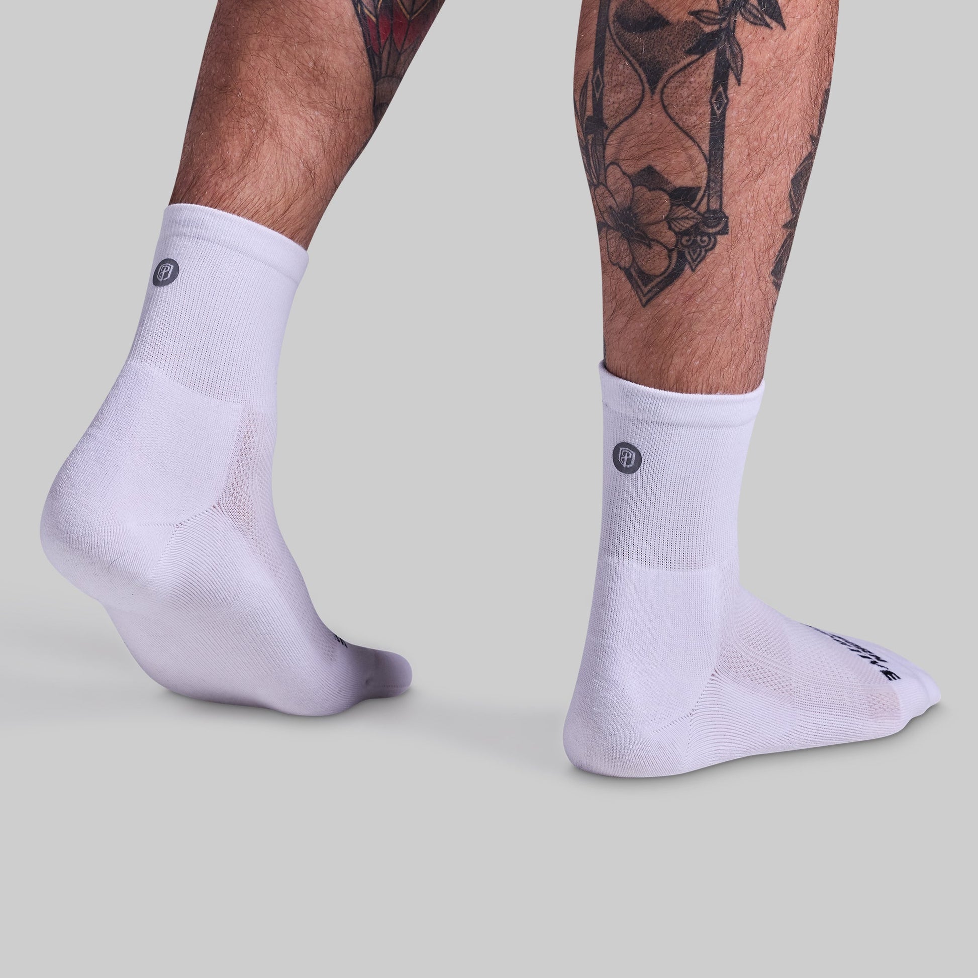 White socks worn by a person with tattoos on a light gray background