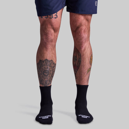 Person wearing black socks with visible tattoos on legs against a gray background