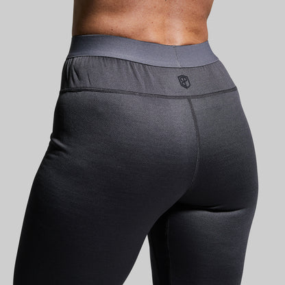 Close-up of a woman wearing gray heavy base layer bottoms on a plain background
