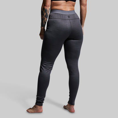 Woman wearing gray heavy base layer bottoms on a plain background