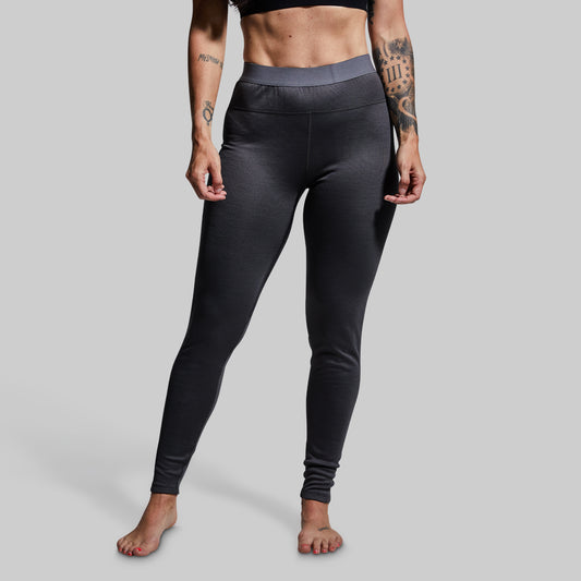 Woman wearing gray heavy base layer bottoms on a plain background