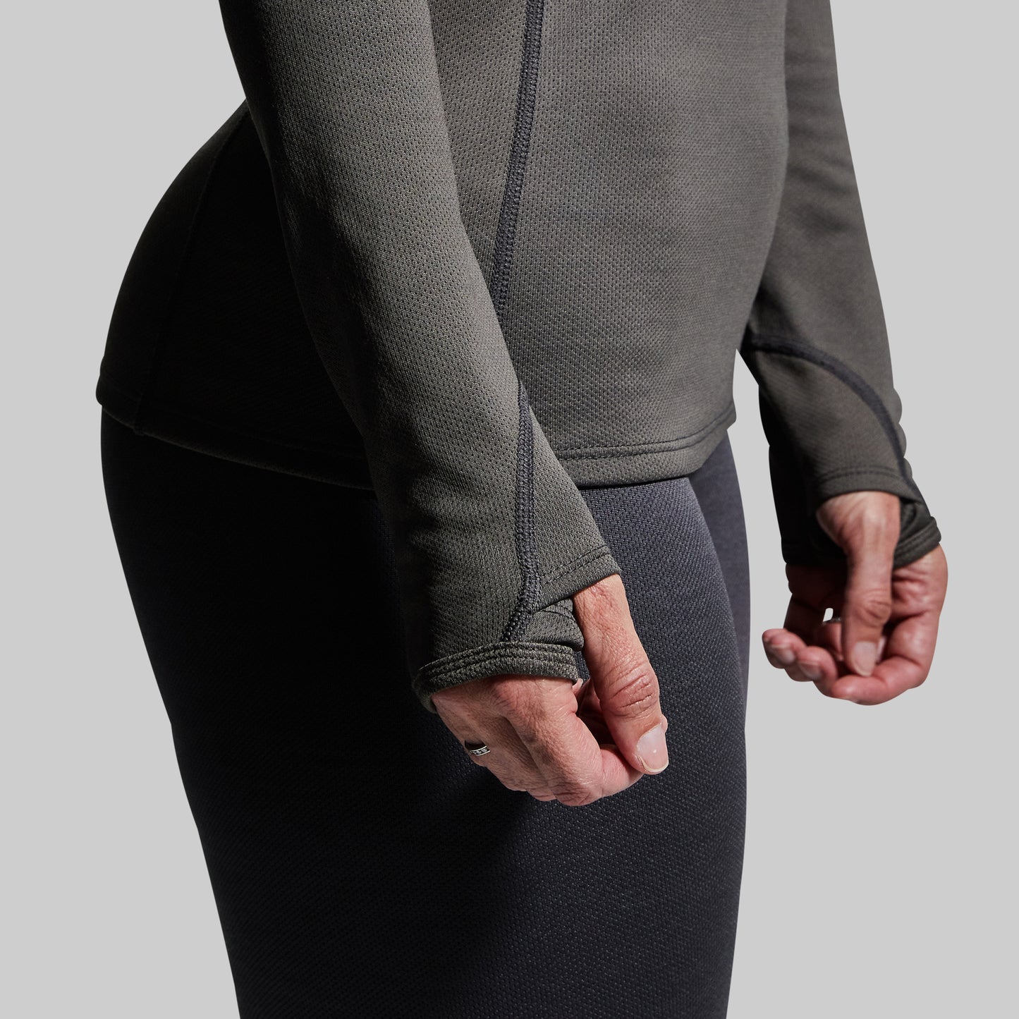 Close-up of thumbholes on gray long-sleeve base layer top.