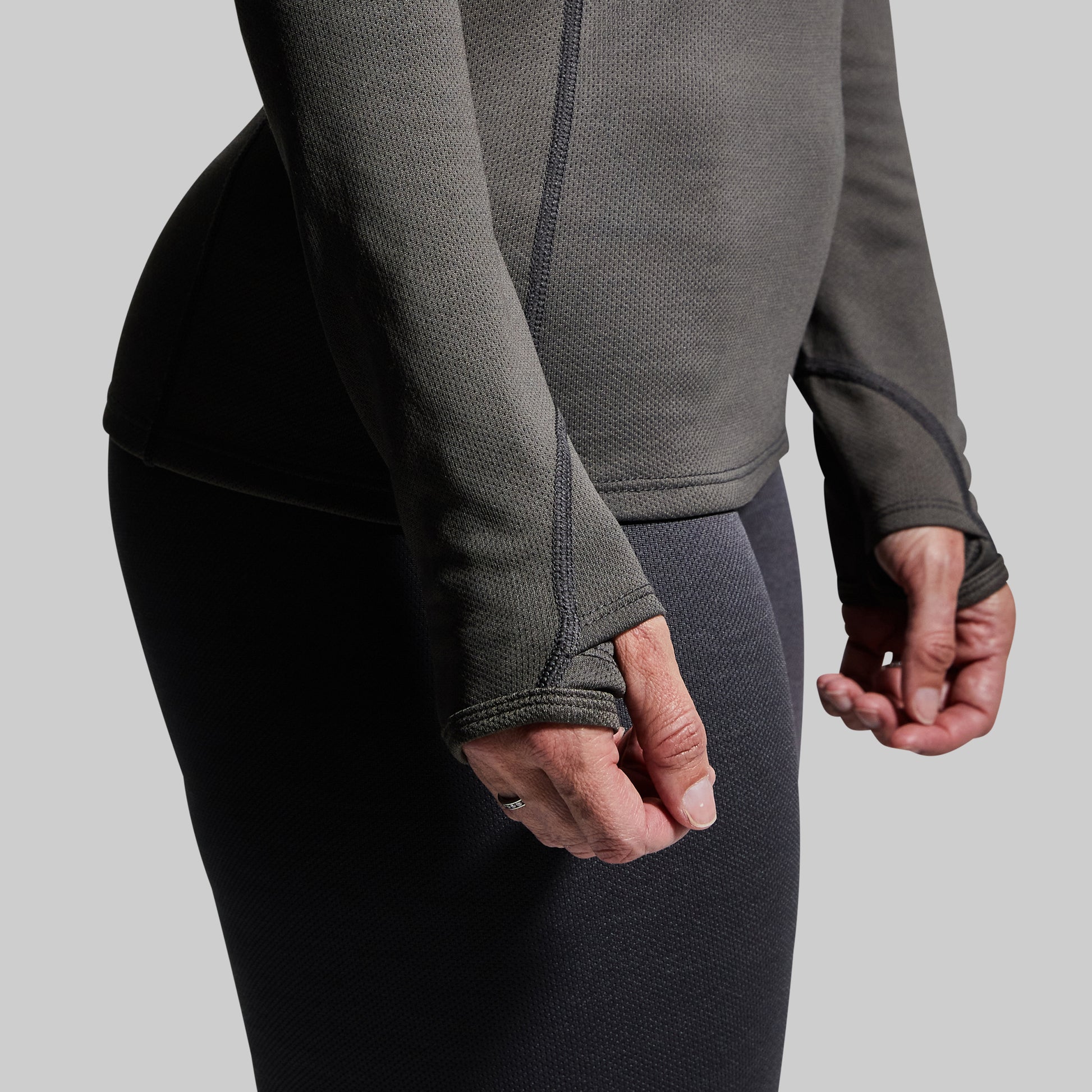 Close-up of thumbholes on gray long-sleeve base layer top.