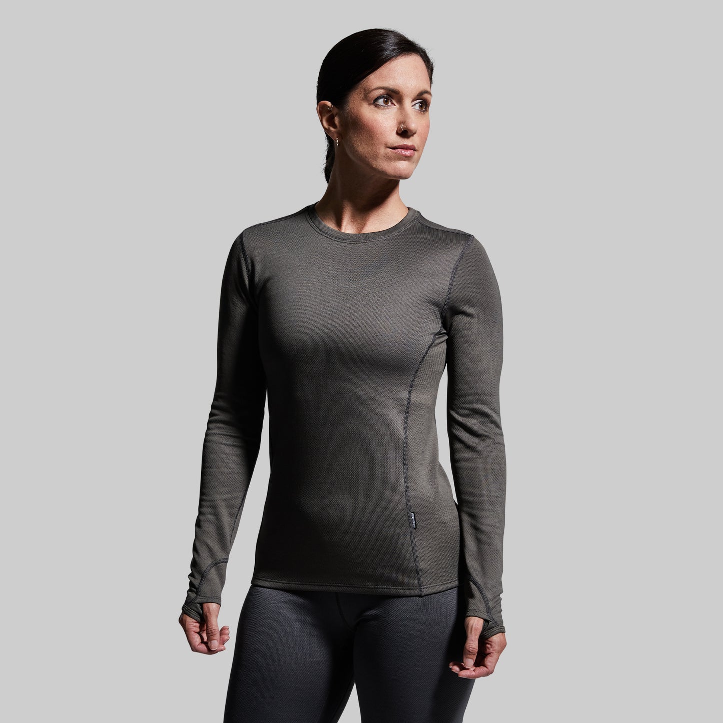 Woman wearing a gray long-sleeve base layer top against a plain background