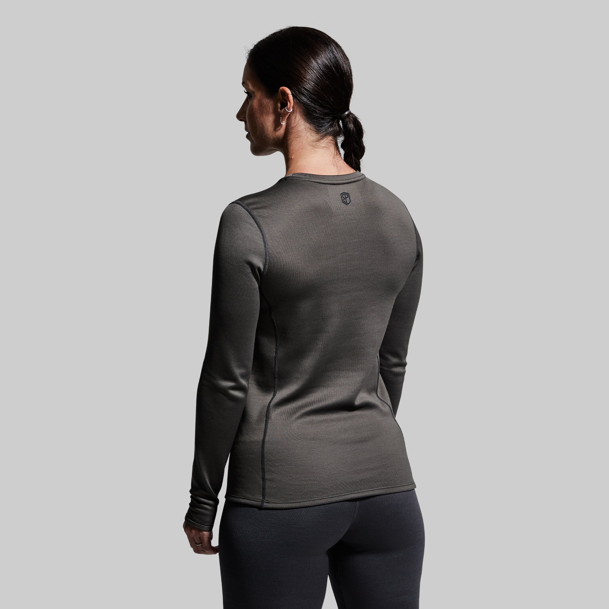 Woman wearing a gray long-sleeve base layer top against a plain background