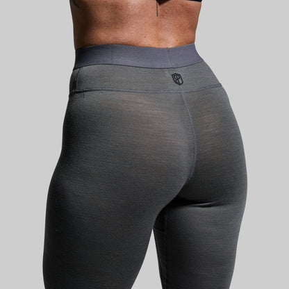 Close-up of a person wearing gray base layer bottoms on a plain background