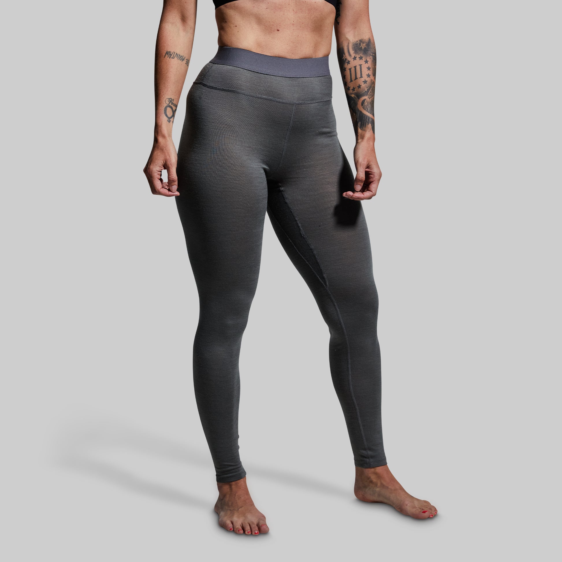 Person wearing gray base layer bottoms on a plain background