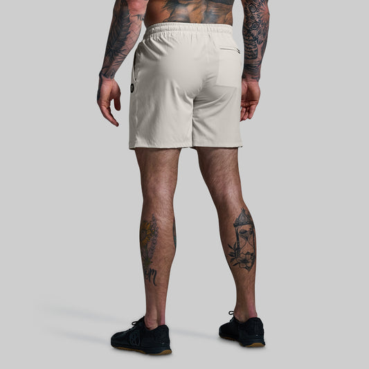 Person wearing beige shorts on a plain background