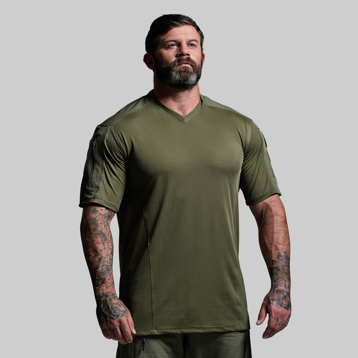 Man wearing an olive green tactical shirt on a gray background