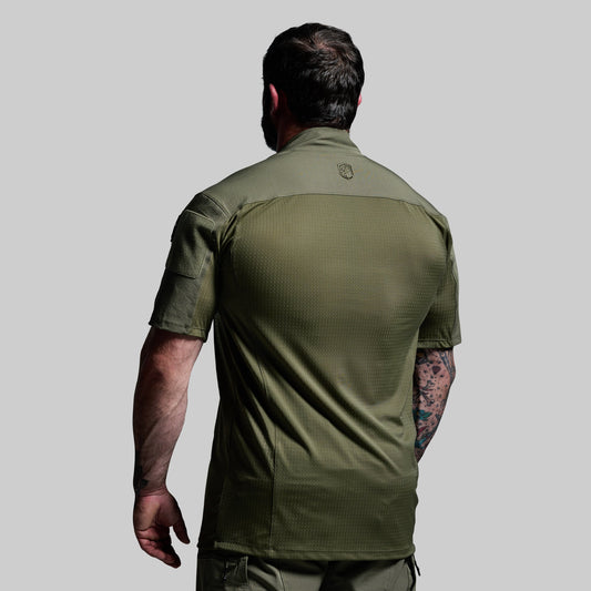 Man wearing a green tactical shirt on a gray background