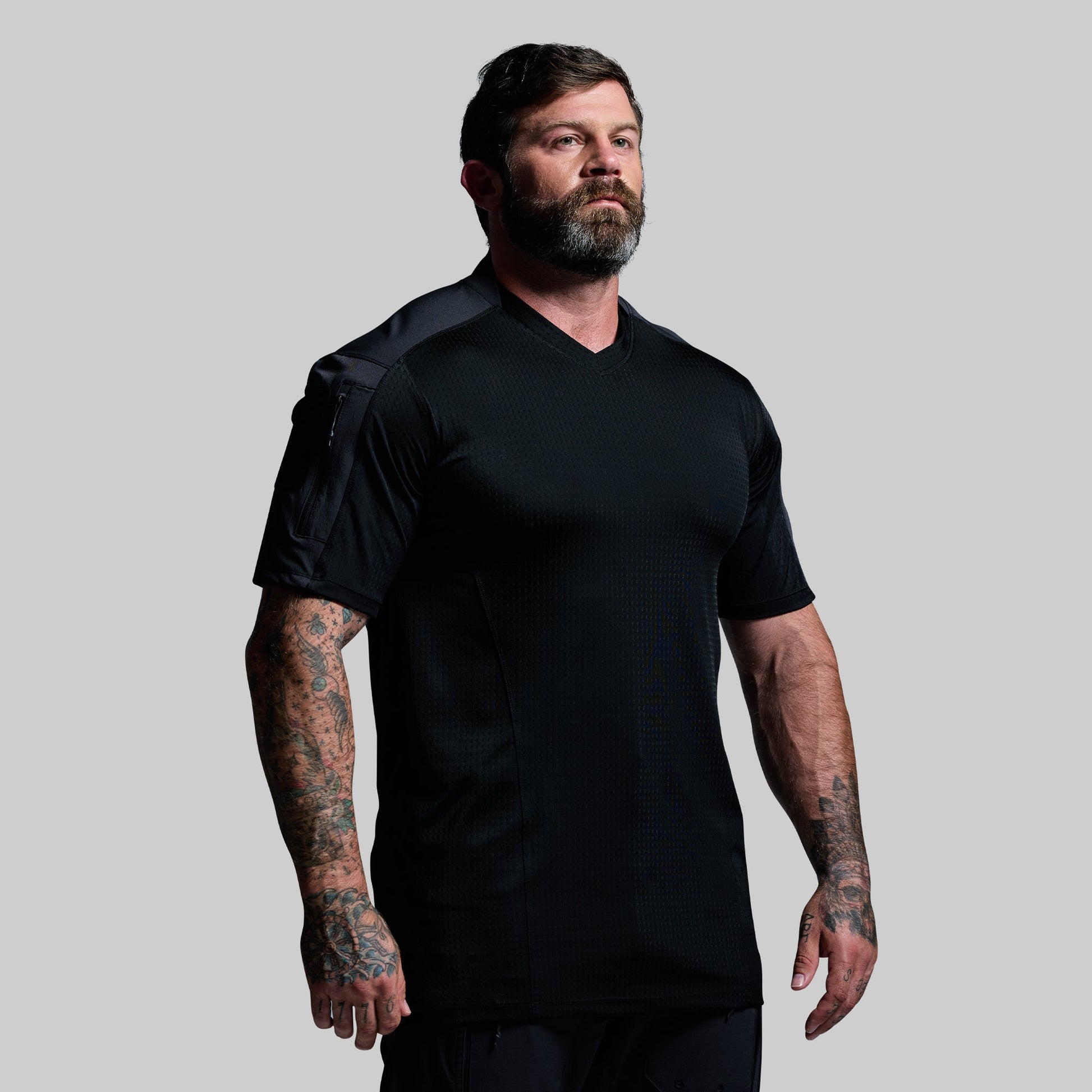 Man wearing a black tactical shirt against a gray background