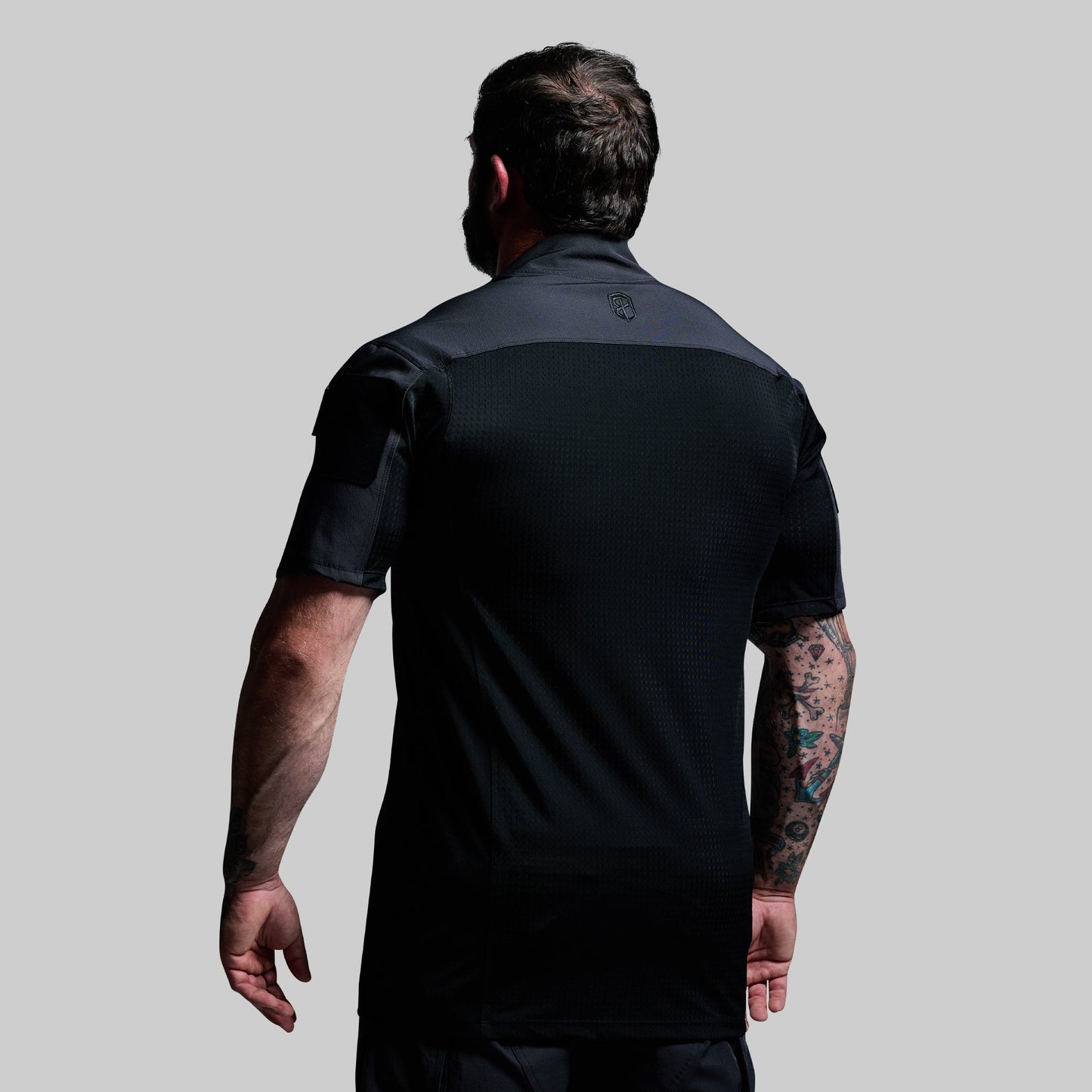 Man wearing a black tactical shirt on a gray background