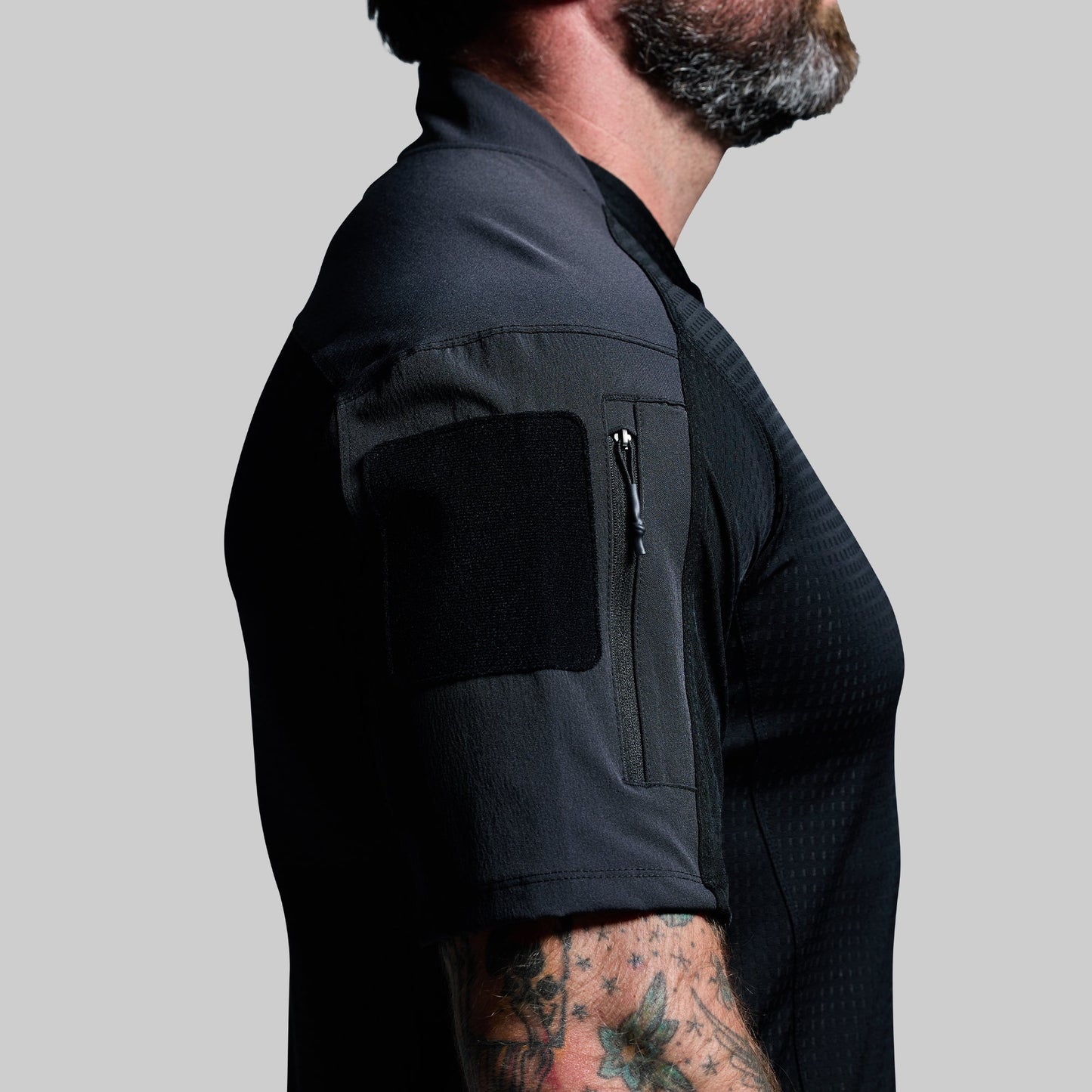Person wearing a black shirt with arm pocket on a gray background