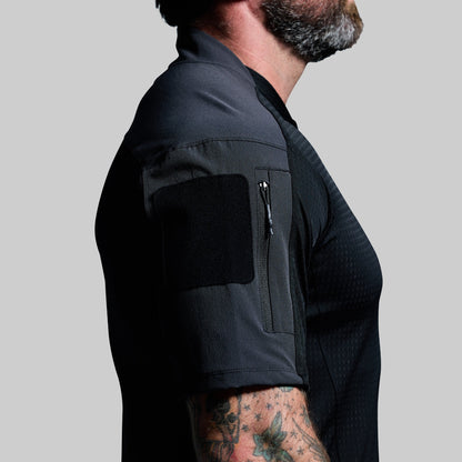 Person wearing a black shirt with arm pocket on a gray background