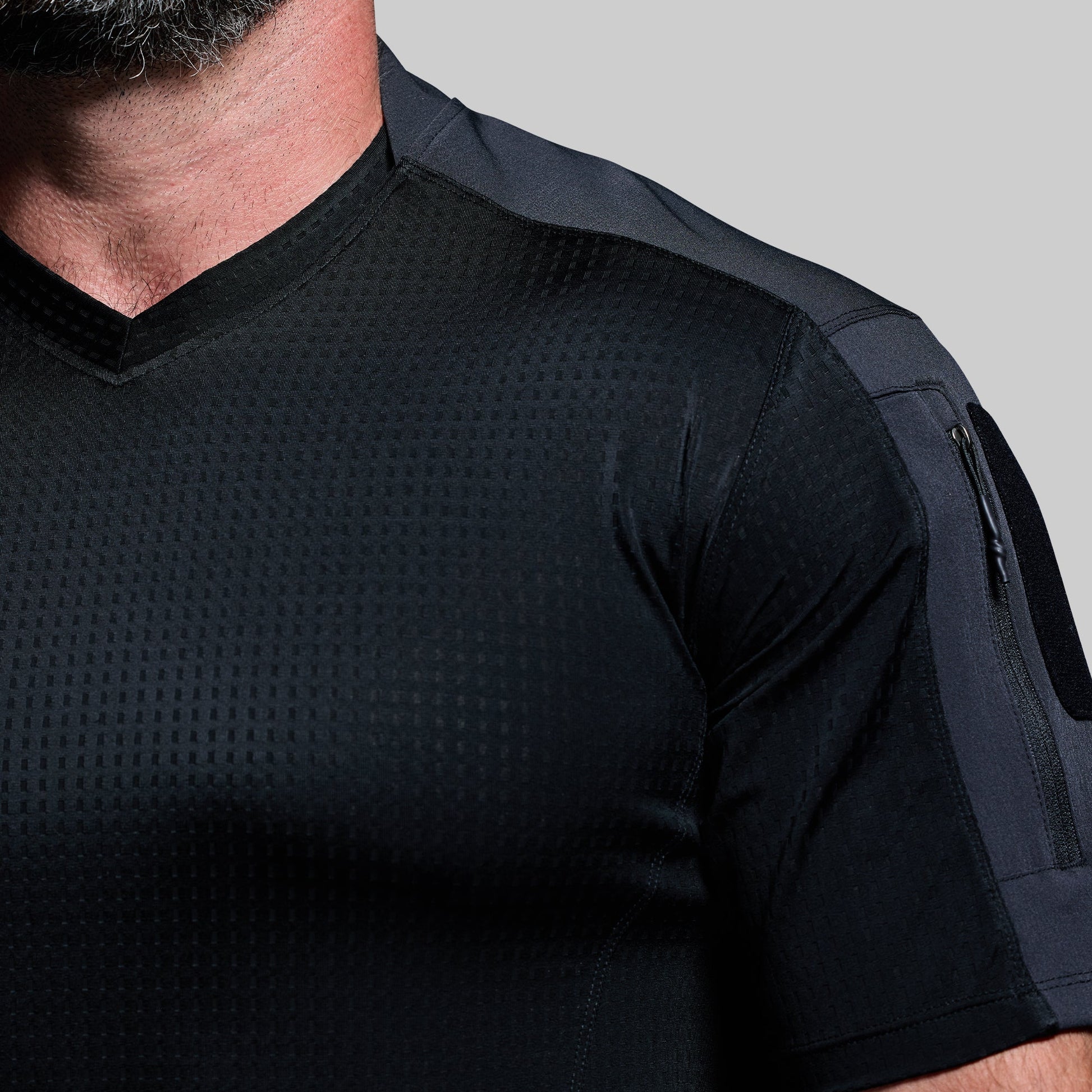 Black tactical shirt with textured design on a gray background