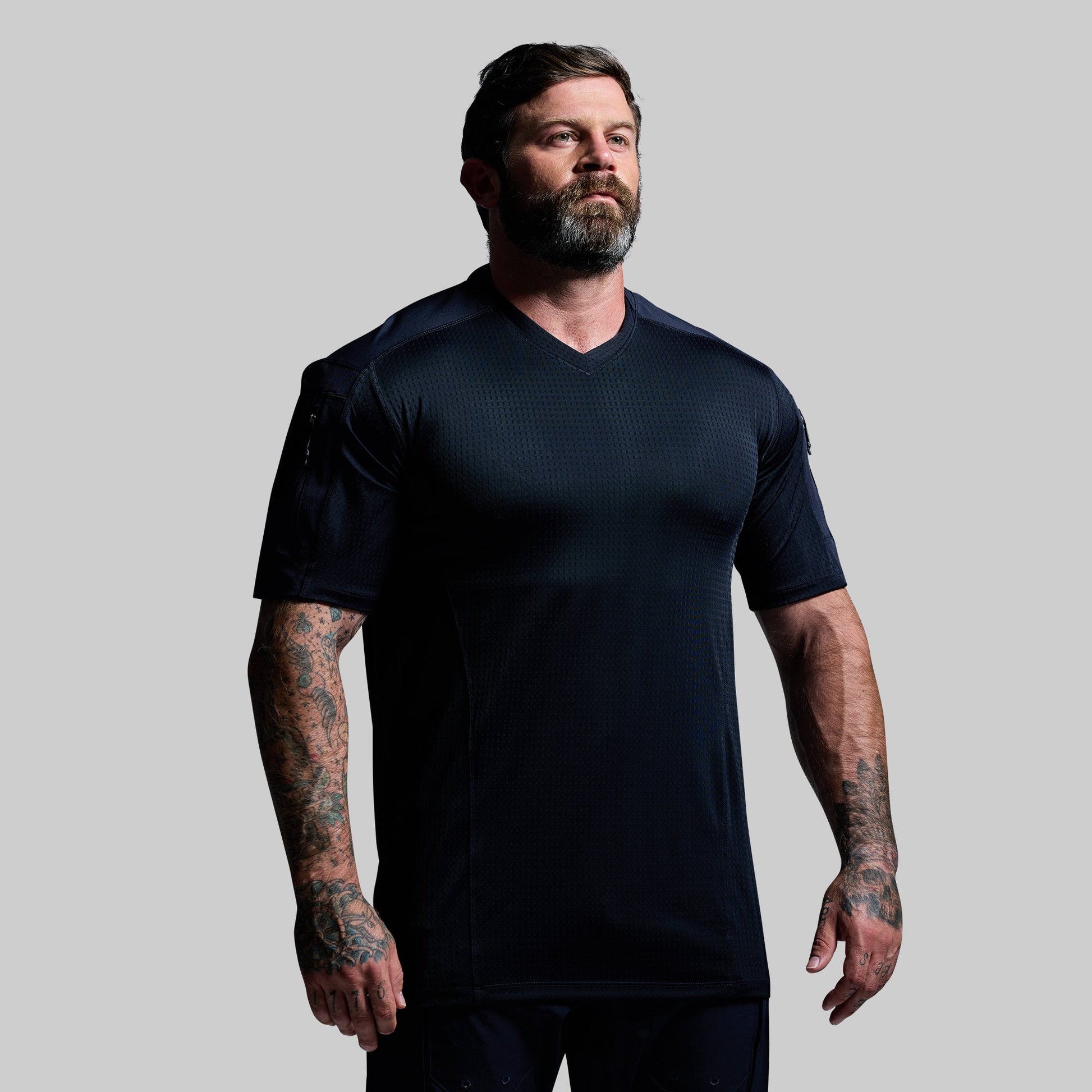 Man wearing a blue tactical t-shirt against a gray background