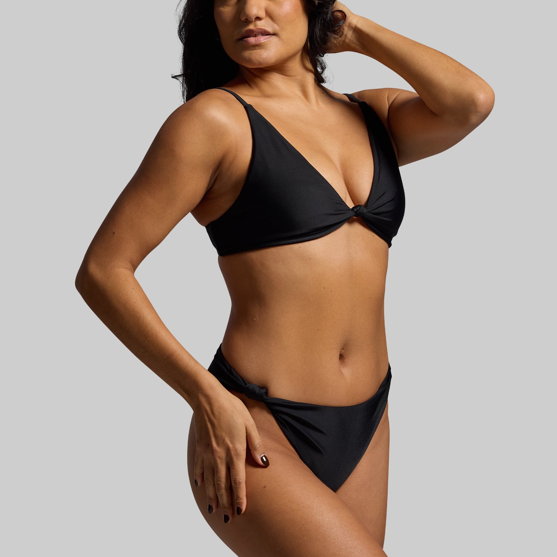 Woman wearing a black bikini against a gray background