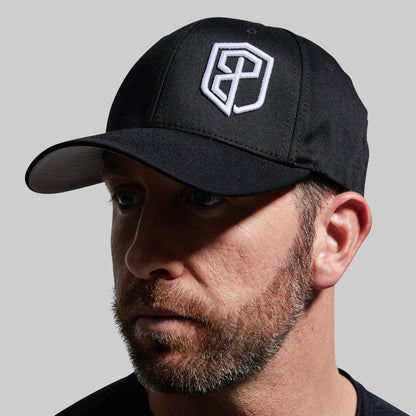 Man wearing a black cap with a white logo on a gray background