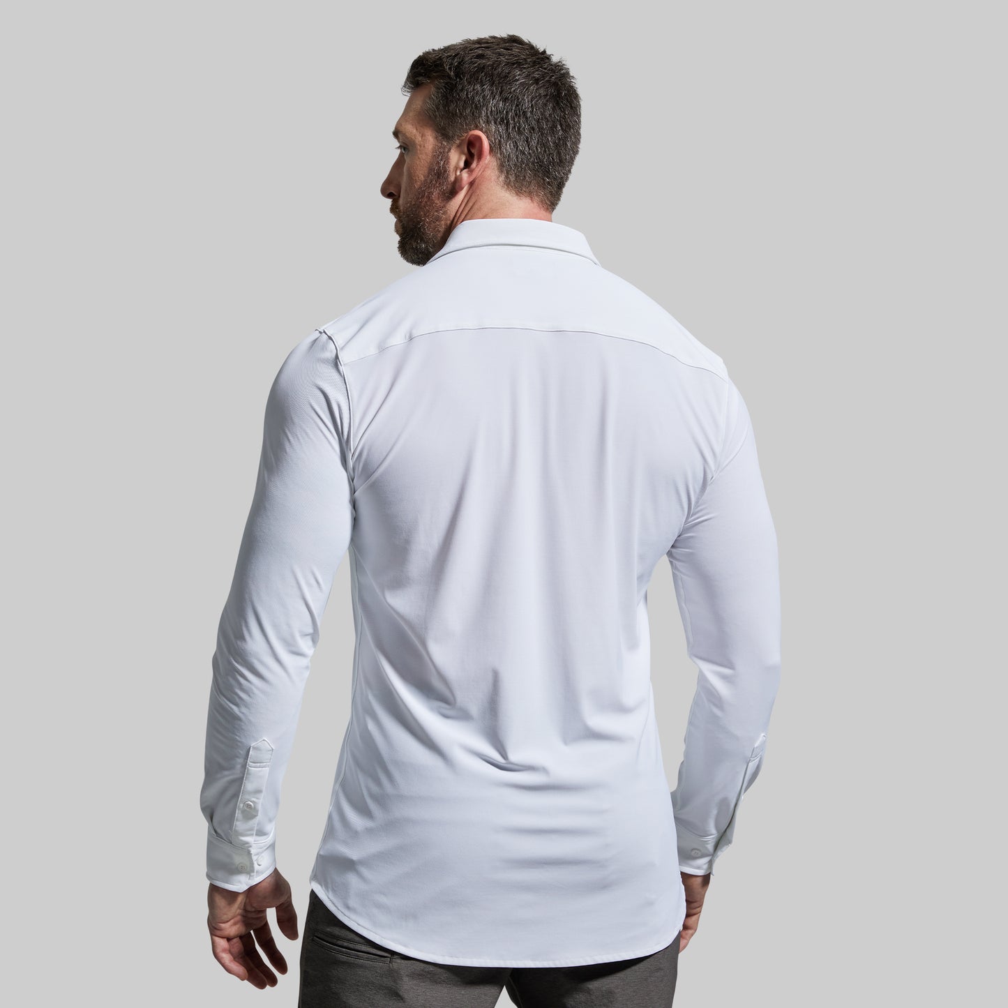 Man wearing a light white long-sleeve shirt against a plain background